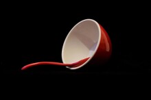 An Empty Toppled Red Bowl With Spoon