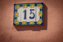 Close-up Of House Number 15 (fifteen), Made Of Ceramic, On The Red Wall In A Small Village. Liguria, Italy, Europe 