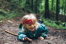 Young Boy With Red Headband Fell Down And Lying On The Dirty Wet Forest Ground