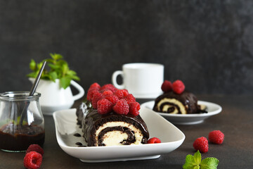 Wall Mural - Chocolate roll with cream cheese and raspberries, with a cup of coffee on a dark background.