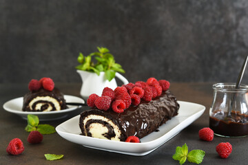 Wall Mural - Chocolate roll with cream cheese and raspberries, with a cup of coffee on a dark background.