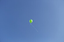 A Single Green Balloon Floating Away On A Clear Day