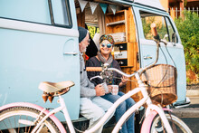 Happy And Cheerful Senior People Couple Enjoy The Travel And Retired Lifestyle Taking A Coffee Together Inside An Old Van With A Bike Outdoor For Healthy Lifestyle - No Limit Age And Traveler