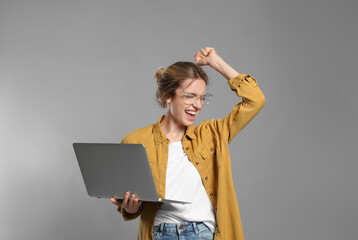 Canvas Print - Portrait of emotional woman with modern laptop on grey background