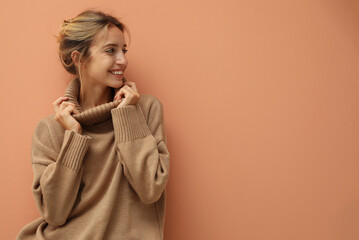 Wall Mural - Beautiful young woman wearing knitted sweater on light brown background. Space for text