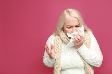 Wall Mural - Mature woman sneezing on pink background, space for text. Cold symptoms