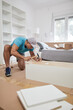 © astrosystem - Man assembling furniture in new apartment, moving in and being hardworking.