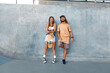 © puhhha - Skaters. Girl And Guy At Skatepark. Portrait Of Hipster Couple In Casual Outfit With Skateboard Against Concrete Wall At Park. Urban Subculture Style And Summer Sport In City. Active Lifestyle.