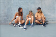 © puhhha - Group Of Skaters With Skateboards. Hipsters In Casual Outfit Sitting Against Concrete Wall At Skatepark. Urban Subculture And Skateboarding As Lifestyle Of Active People In City.