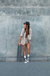 © puhhha - Skater Girl At Skatepark. Full-Length Portrait Of Female Hipster In Casual Outfit With Skateboard. Teenager Looking Away Against Concrete Wall At Skate Park. Urban Subculture Style And Summer Sport.