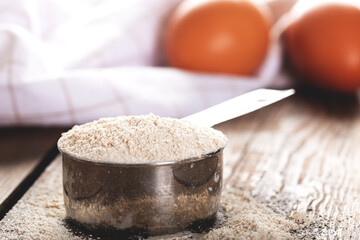 Einkorn siyez whole wheat flour in metal measuring cup on natural background.