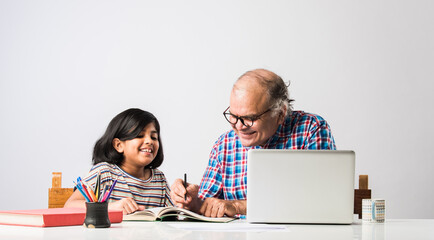 Indian asian Grandfather is teaching his granddaughter or grandaughter at home