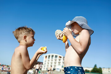 Wall Mural - Brothers eating boiled corn on beach