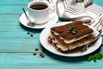 portion of Classic tiramisu dessert, cup of coffee and milk or cream on wooden background