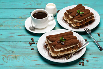 Two portions of Classic tiramisu dessert, cup of coffee and milk or cream on colorful blue wooden background