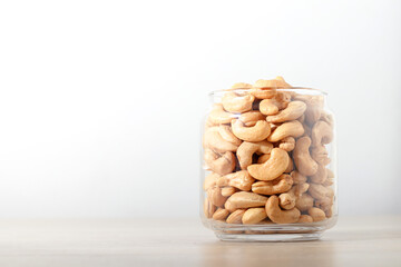 Cashew nuts in glass bottles Placed on a wooden floor. Food photography concept. Copy space