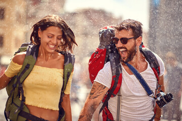 Young cheerful tourist couple enjoying the fountain shower