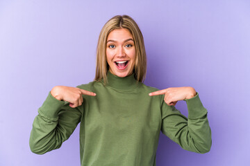 Poster - Young blonde caucasian woman isolated surprised pointing with finger, smiling broadly.