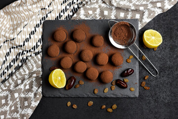 Wall Mural - Homemade vegan truffles with dried fruits, walnuts and raw cocoa powder served on black slate plate.