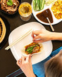 Asian cuisine and food in restaurant with hands and white wine top angle