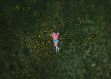 Ariel View Of A Child Laying In The Grass With Dandelions 