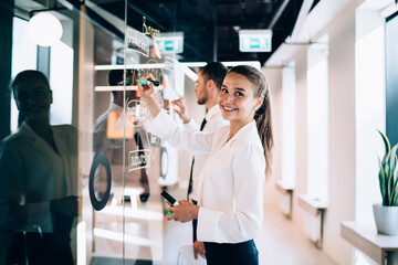 Wall Mural - Young female office worker writing on wall and smiling