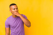© Asier - Young latin man isolated on yellow background thoughtful looking to a copy space covering mouth with hand.