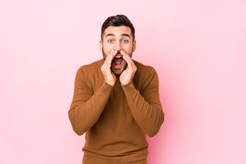 Wall Mural - Young caucasian man against a pink background isolated shouting excited to front.