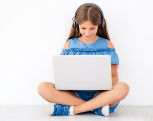 Wall Mural - Child sitting on floor studying on laptop