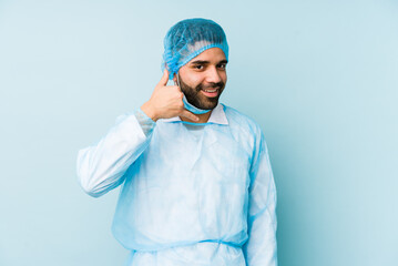 Wall Mural - Young surgeon latin man isolated Young dshowing a mobile phone call gesture with fingers.