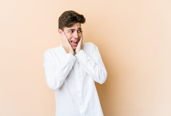 Wall Mural - Young caucasian man isolated on beige background scared and afraid.