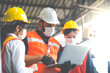 © NVB Stocker - Engineers people are brainstorming solving problems of heavy industrial machinery. Worker man and asian woman wearing face mask prevent covid-19 virus and protective hard hat. .