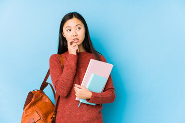 Young chinese student woman isolated relaxed thinking about something looking at a copy space.