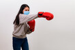 © PK Studio - Asian beautiful happy young woman wearing mask protection and boxing gloves her get ready for Coronavirus fighting against, with copy space