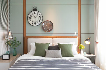 Modern green and brown bedroom with striped pattern. large wall clock on wall.