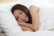 © sopradit - Asian women wake up happy and smile on white bed in bedroom.