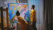 © DC Studio - Man and woman painters working together in art studio on large canvas.