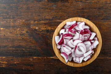 Canvas Print - Sliced raw red onion in a bowl on a wooden background. Vegetable, ingredient and staple food.