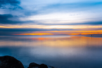 Wall Mural - Clean minimalist long exposure sunset over sea and rocks with beautiful reflections and text space