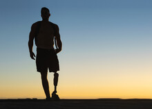 Silhouette Of Athletic Man With Prosthetic Leg With Sunset Sky At Background