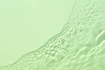 Closeup of mint green transparent clear calm water surface texture with splashes and bubbles. Trendy abstract summer nature background. Mint colored waves in sunlight. Copy space.