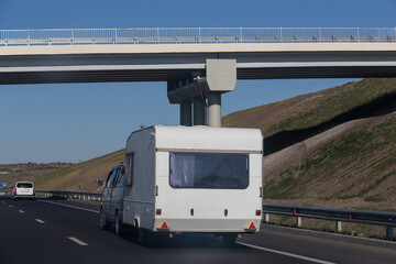 Wall Mural - Car with a camper trailer is moving along highway