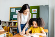 © JR-50 - An Asian woman teacher teaches an African American child student a lesson in the classroom. They smile happily during the lessons learned. School diversity student