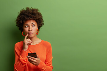 photo of pretty ethnic woman ponders on how to answer question, thinks deeply about something, uses 
