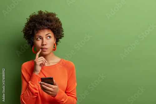 Fotografía Photo of pretty ethnic woman ponders on how to answer question, thinks deeply ab