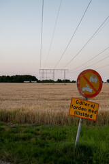 Wall Mural - An old sign informing drivers that they are not allowed to enter the rural road next to an agricultural field with power lines in southern Sweden