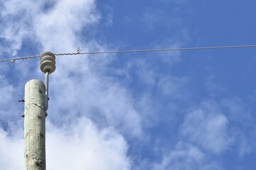 Power line with glass insulators and wires. One power pole off center, room for copy.  Blue sky in background.