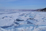 Fototapeta Na ścianę - large iridescent crystals white blue ice floes with cracks glow in the light of the sun, lake baikal in winter, mountains on the horizon, blue sky, snow