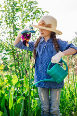 Little cute girl watering trees and flowers