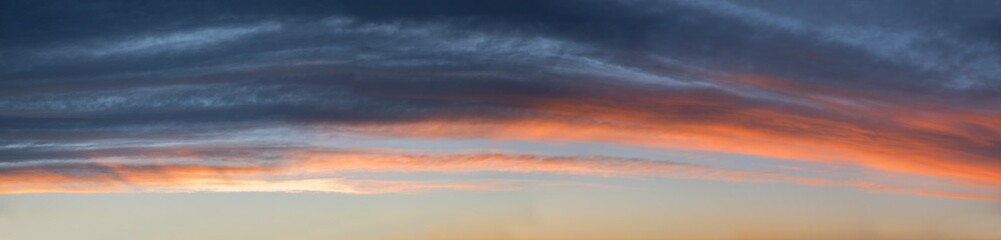 Wall Mural - wide sky panorama with gray and orange clouds, above blue sky